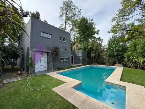 Casa de 5 ambientes con jardín frente y fondo, pileta , quincho y cochera en barrio cerrado.